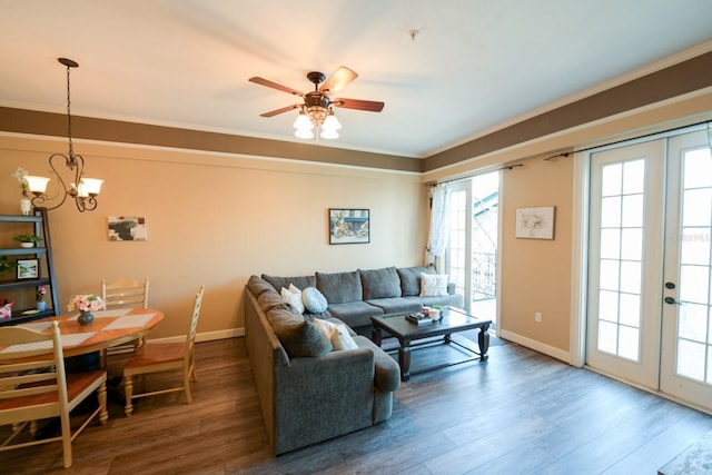 living room featuring ceiling fan with notable chandelier, wood finished floors, baseboards, french doors, and crown molding