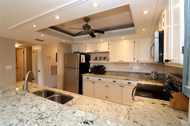 kitchen featuring a sink, stainless steel appliances, tasteful backsplash, and a raised ceiling