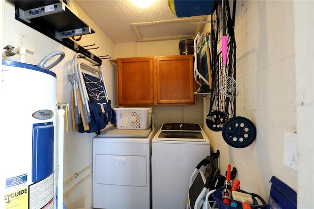 clothes washing area with cabinet space, water heater, washer and clothes dryer, and a textured ceiling