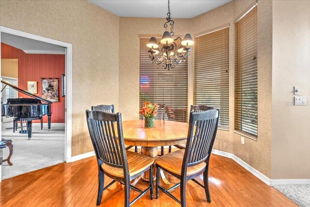 dining room featuring a chandelier, wood-type flooring, and baseboards