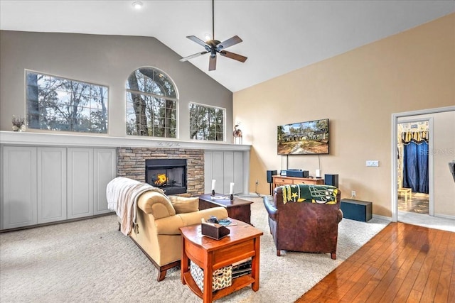 living room with a ceiling fan, a fireplace, light wood-style flooring, and high vaulted ceiling