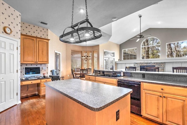 kitchen featuring a sink, vaulted ceiling, light wood-type flooring, a center island, and dark countertops