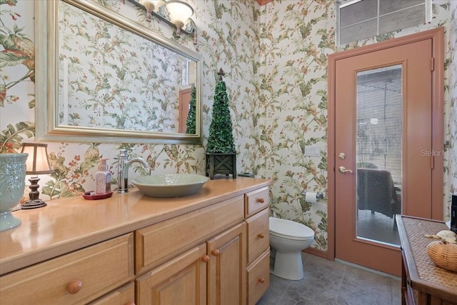 bathroom featuring toilet, wallpapered walls, tile patterned floors, and vanity