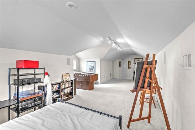 carpeted bedroom with rail lighting and vaulted ceiling