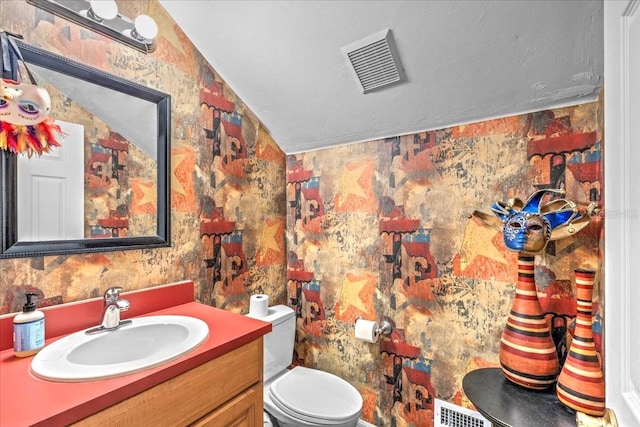 bathroom featuring visible vents, vanity, toilet, and wallpapered walls