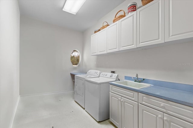 washroom featuring cabinet space, baseboards, a sink, and washing machine and clothes dryer