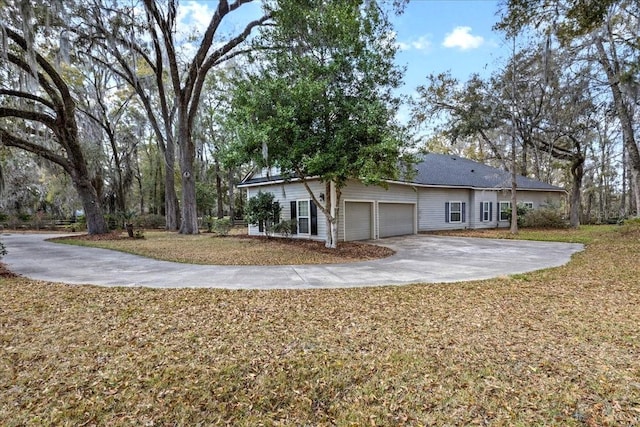 rear view of house featuring driveway, an attached garage, and a lawn