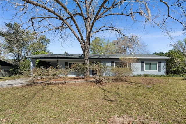 ranch-style home featuring concrete driveway, an attached carport, and a front yard