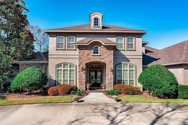 view of front of house featuring stucco siding, stone siding, and french doors