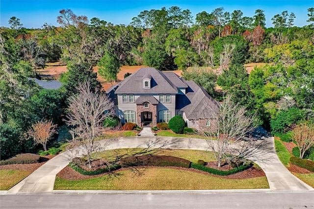 view of front of property with stone siding, concrete driveway, and a front lawn