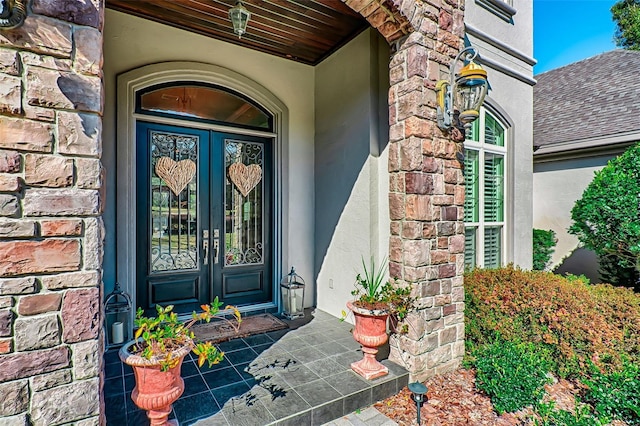 property entrance with french doors, brick siding, and stucco siding