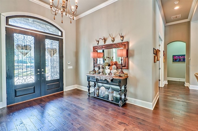 foyer with arched walkways, ornamental molding, visible vents, and hardwood / wood-style floors