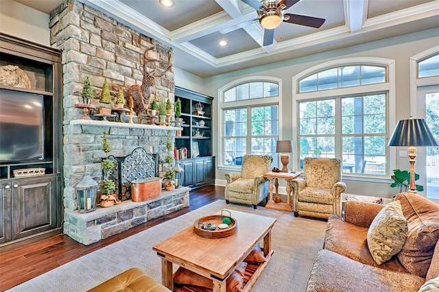 living room featuring a wealth of natural light, beam ceiling, a stone fireplace, and wood finished floors