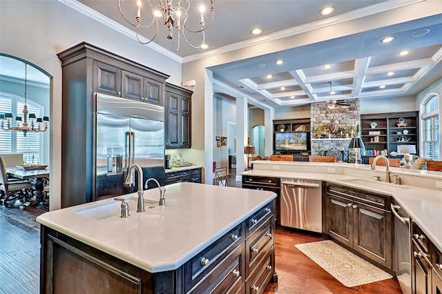 kitchen with appliances with stainless steel finishes, coffered ceiling, a sink, and open floor plan