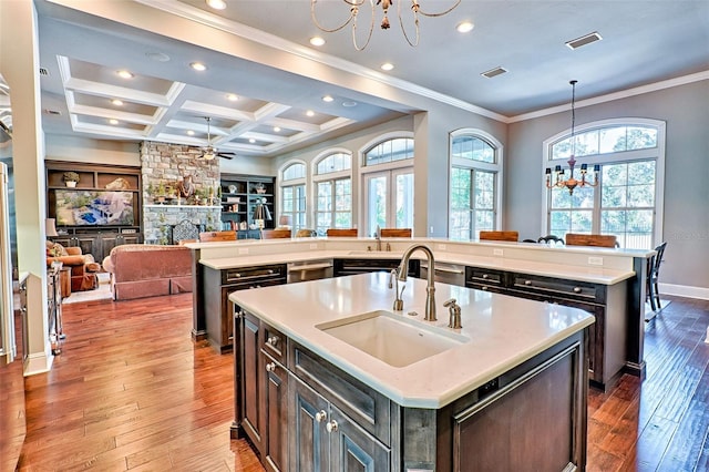 kitchen featuring visible vents, coffered ceiling, hardwood / wood-style flooring, a large island, and a sink