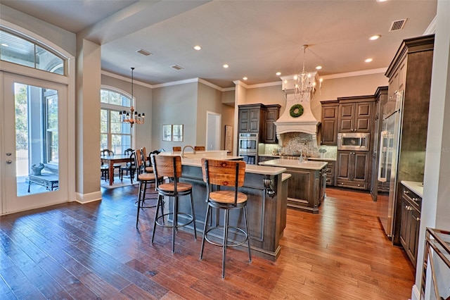 kitchen featuring an inviting chandelier, visible vents, a large island with sink, and built in appliances