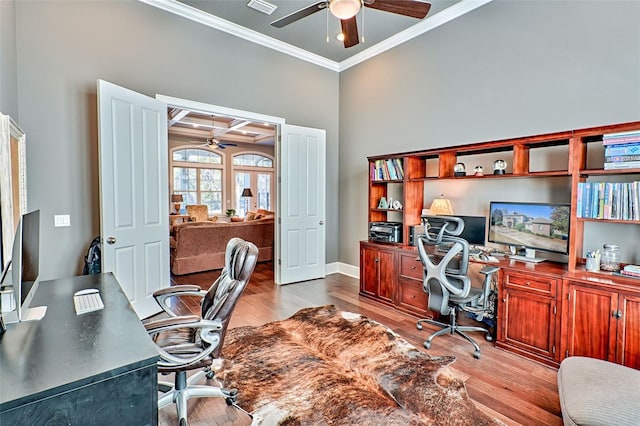 home office featuring crown molding, visible vents, a ceiling fan, wood finished floors, and baseboards