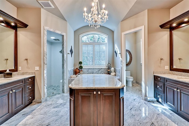 bathroom featuring visible vents, toilet, marble finish floor, vaulted ceiling, and two vanities