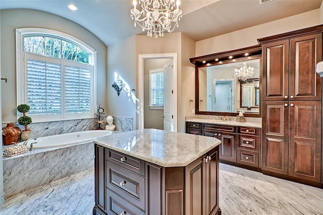 bathroom with an inviting chandelier, marble finish floor, a bath, and vanity