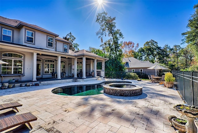 view of pool with a patio area, fence, and a pool with connected hot tub