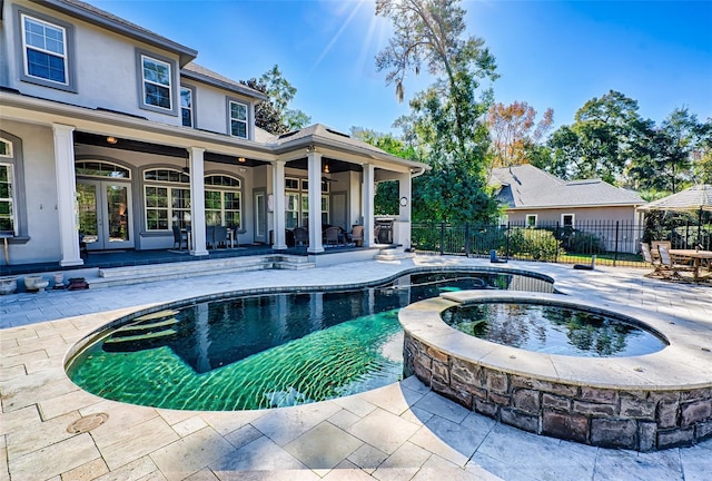 view of pool with an in ground hot tub, fence, a patio, and french doors