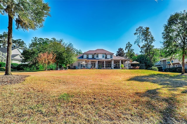 rear view of property featuring a porch and a yard