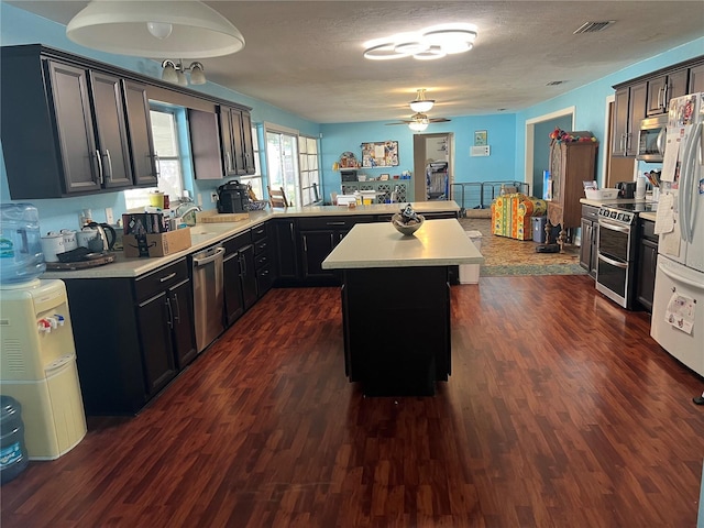 kitchen featuring dark wood-style floors, appliances with stainless steel finishes, light countertops, and a peninsula