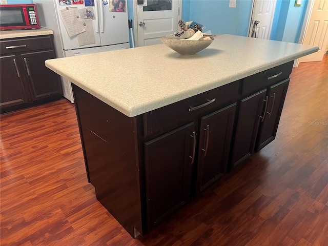 kitchen with dark wood finished floors, light countertops, freestanding refrigerator, and a kitchen island