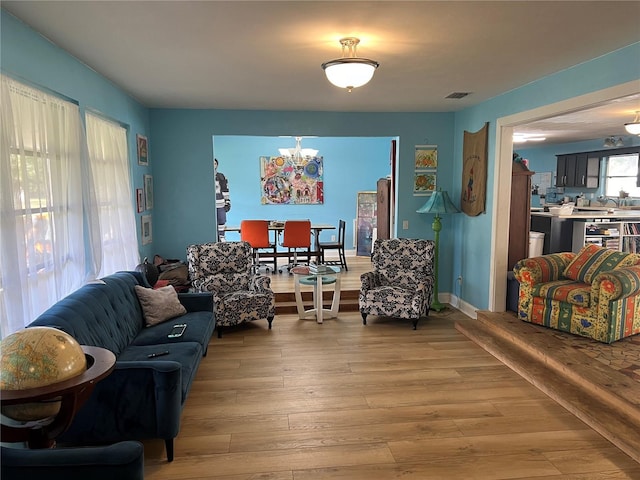 living room featuring visible vents, an inviting chandelier, and light wood-style flooring