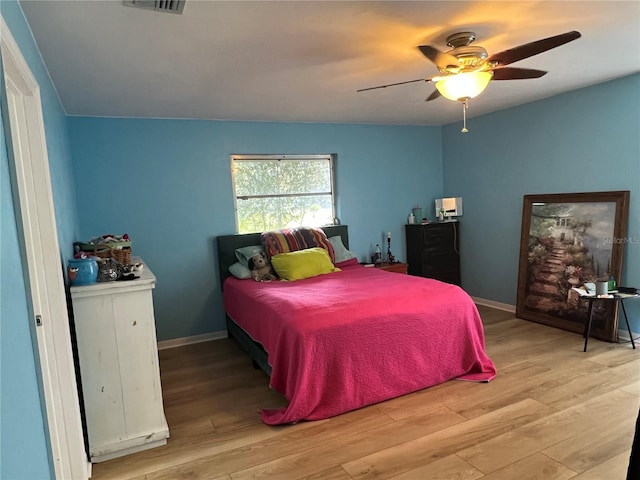 bedroom with visible vents, light wood-style flooring, a ceiling fan, and baseboards