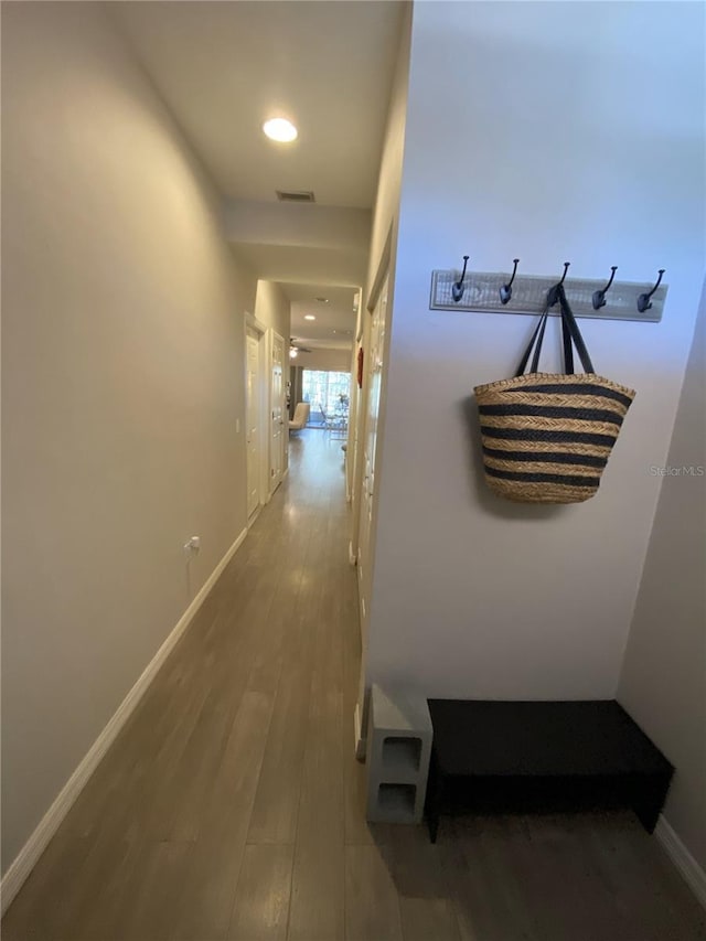 hallway featuring visible vents, recessed lighting, baseboards, and wood finished floors