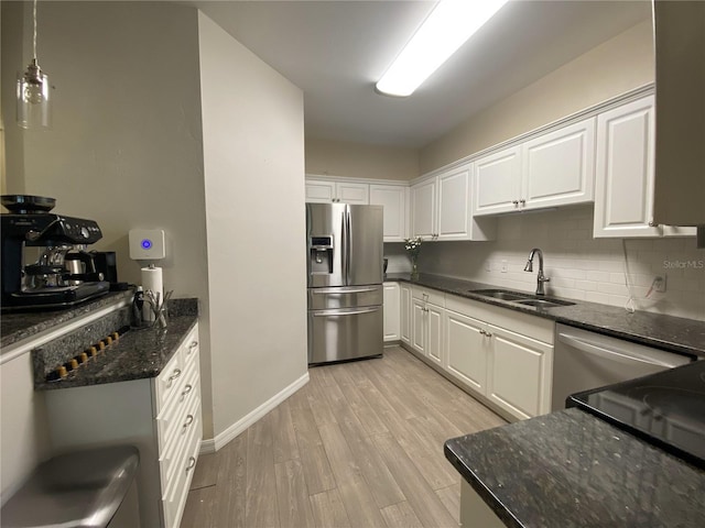 kitchen with stainless steel fridge with ice dispenser, a sink, light wood-style floors, white cabinetry, and backsplash