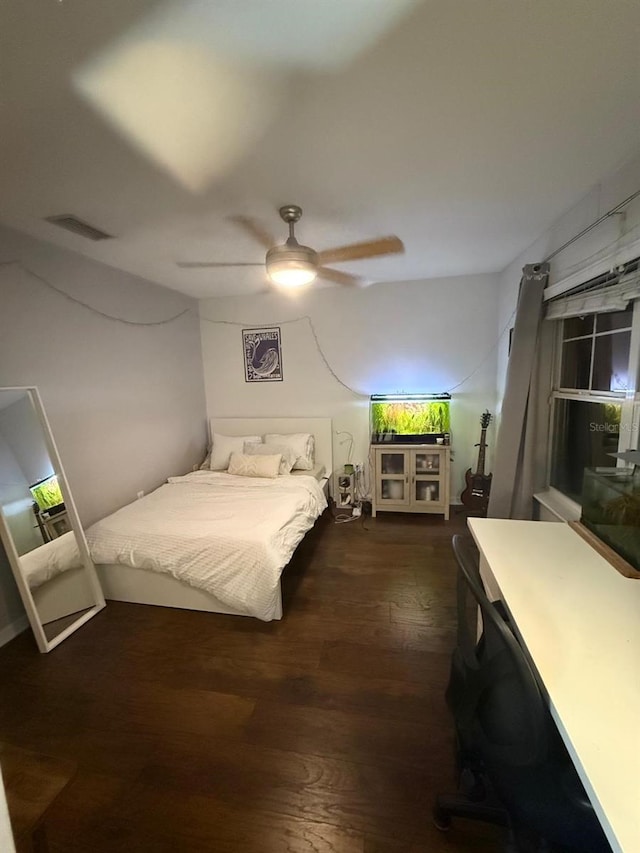 bedroom with ceiling fan, visible vents, and wood finished floors