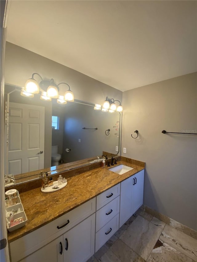 full bath with a sink, baseboards, toilet, and double vanity