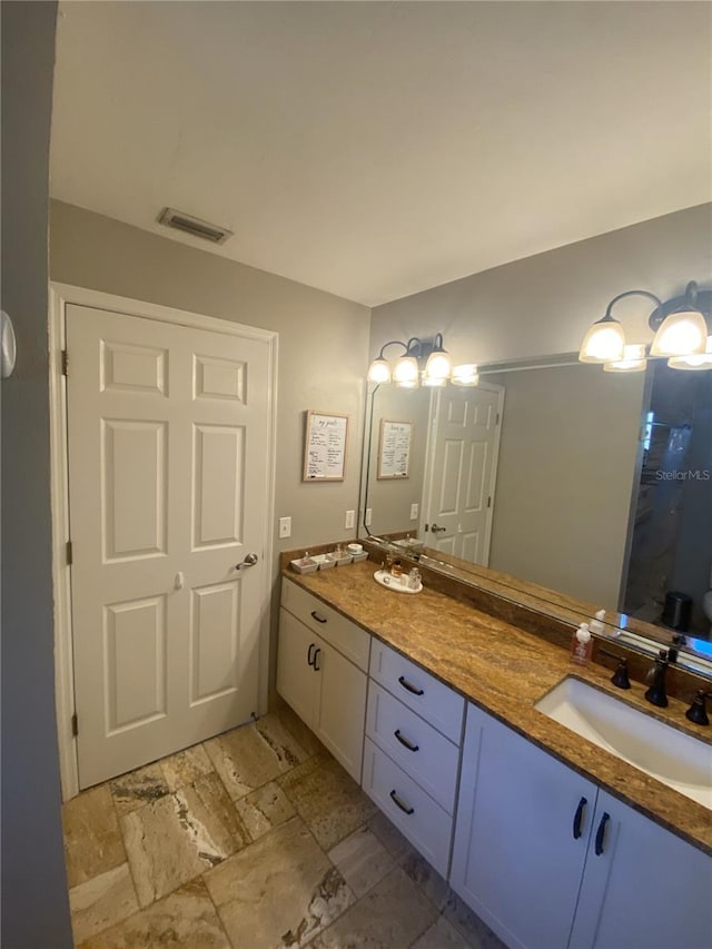 bathroom featuring double vanity, walk in shower, visible vents, and a sink