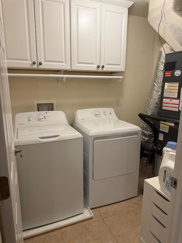 laundry room with washer and dryer, cabinet space, and light tile patterned flooring