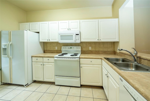 kitchen with white appliances, light tile patterned floors, a sink, white cabinetry, and backsplash