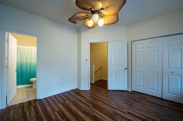 unfurnished bedroom with baseboards, dark wood finished floors, ceiling fan, ensuite bath, and a closet