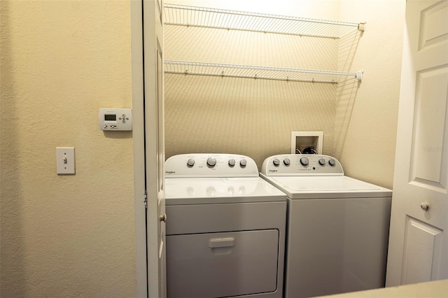 laundry area with laundry area, separate washer and dryer, and a textured wall