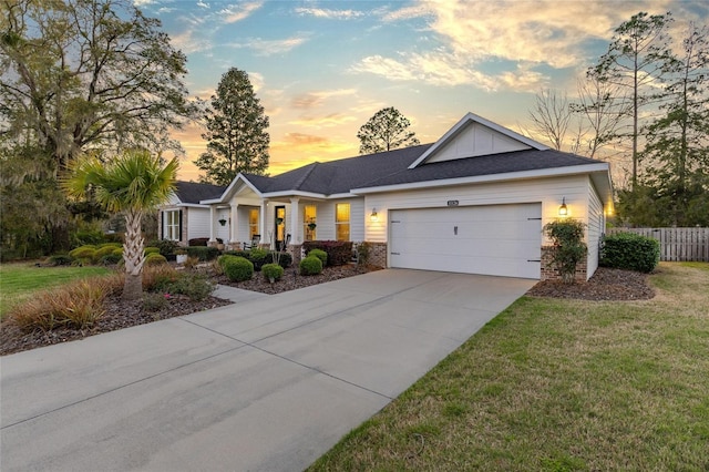 ranch-style home featuring fence, an attached garage, concrete driveway, a lawn, and board and batten siding