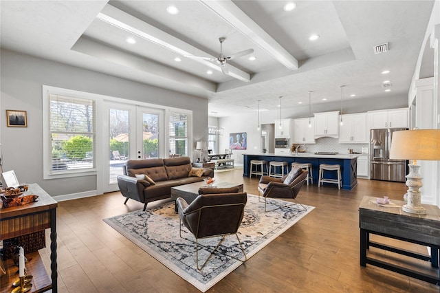 living area with visible vents, a raised ceiling, and dark wood-style flooring