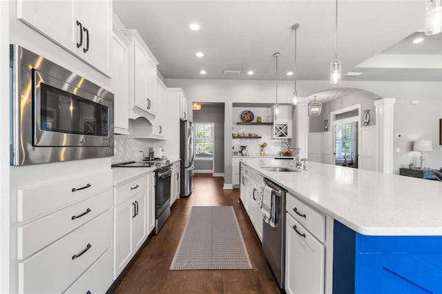 kitchen featuring a sink, open shelves, recessed lighting, stainless steel appliances, and arched walkways