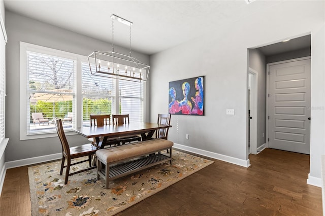 dining area featuring a notable chandelier, baseboards, and wood finished floors