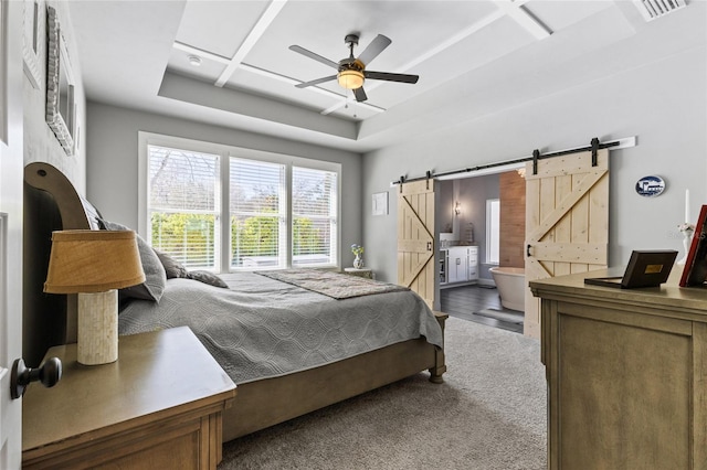 carpeted bedroom with visible vents, ceiling fan, ensuite bathroom, a barn door, and a raised ceiling