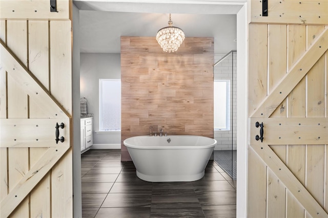 bathroom featuring an inviting chandelier, tile patterned floors, and a freestanding bath