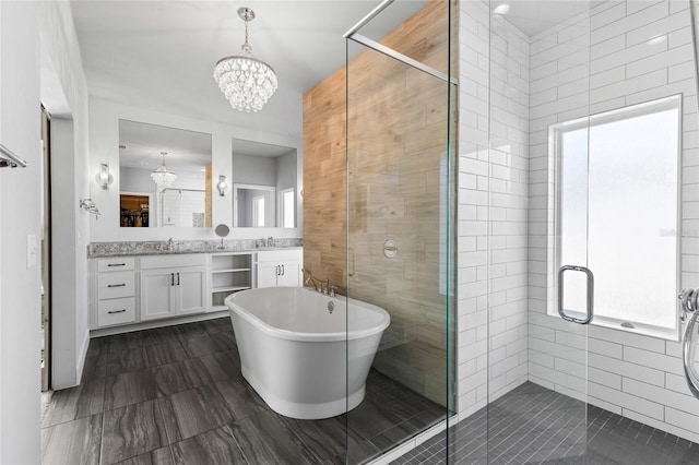 bathroom with vanity, an inviting chandelier, a freestanding tub, a stall shower, and tile walls