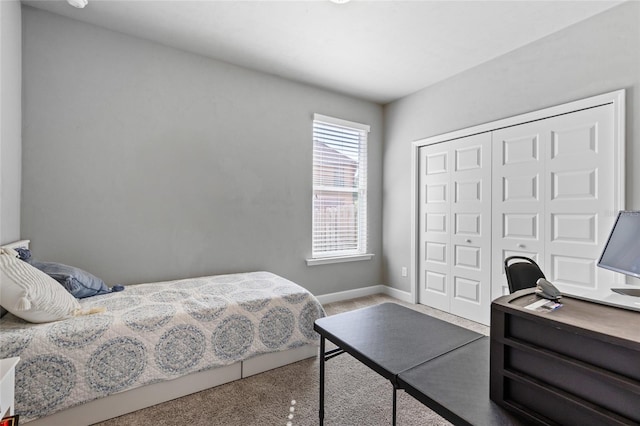 carpeted bedroom with baseboards and a closet