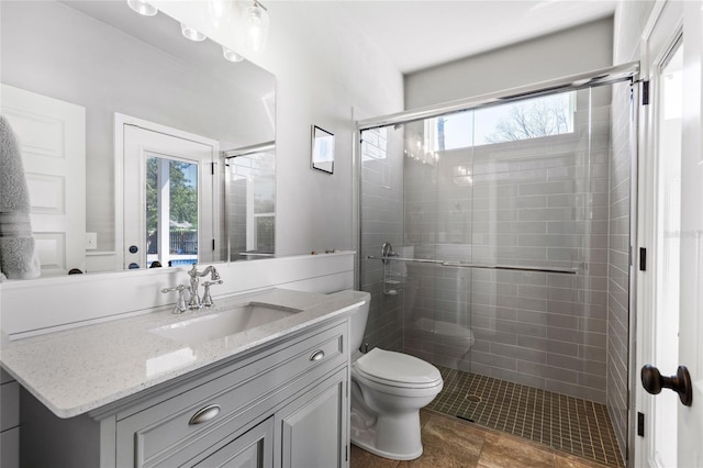 full bath with plenty of natural light, toilet, a stall shower, and vanity