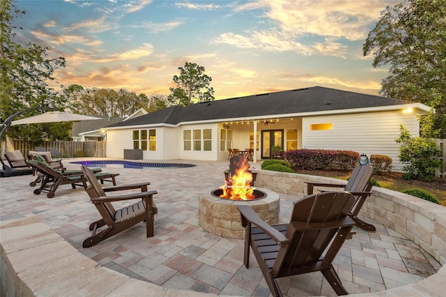 rear view of house with a fenced in pool, a patio, a fire pit, and fence