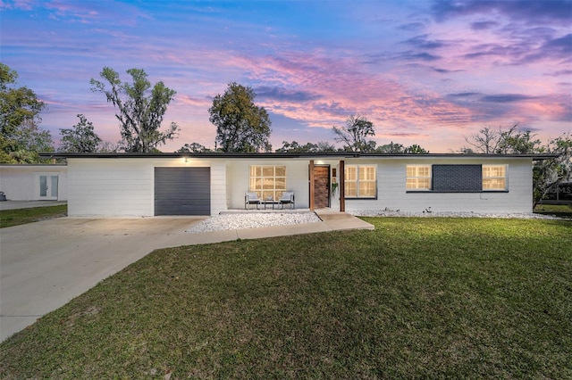 ranch-style home with a garage, a yard, and concrete driveway